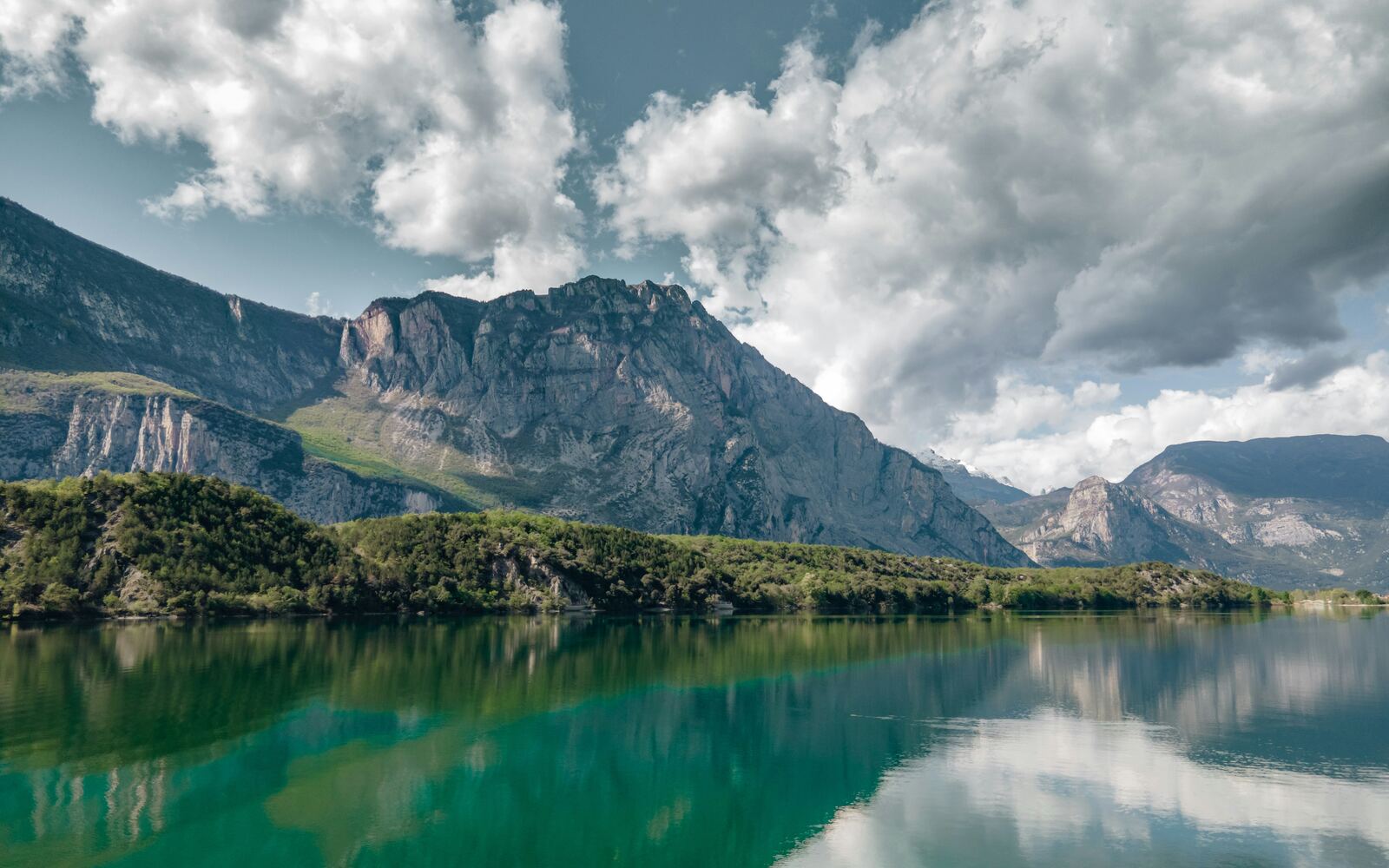 Mountain lake reflecting cliffs and clouds